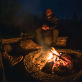 Mand oplyst af bålet i den mørke nattehimmel