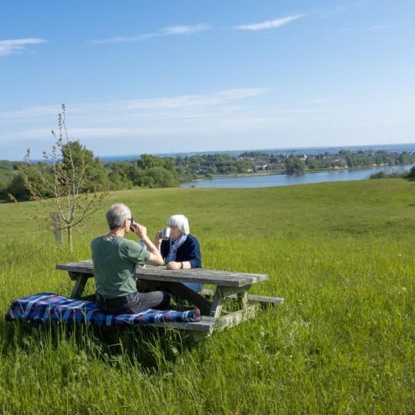 Ældre ægtepar sidder og drikker kaffe ved borde bænke sæt ved Sundsøen Faaborg
